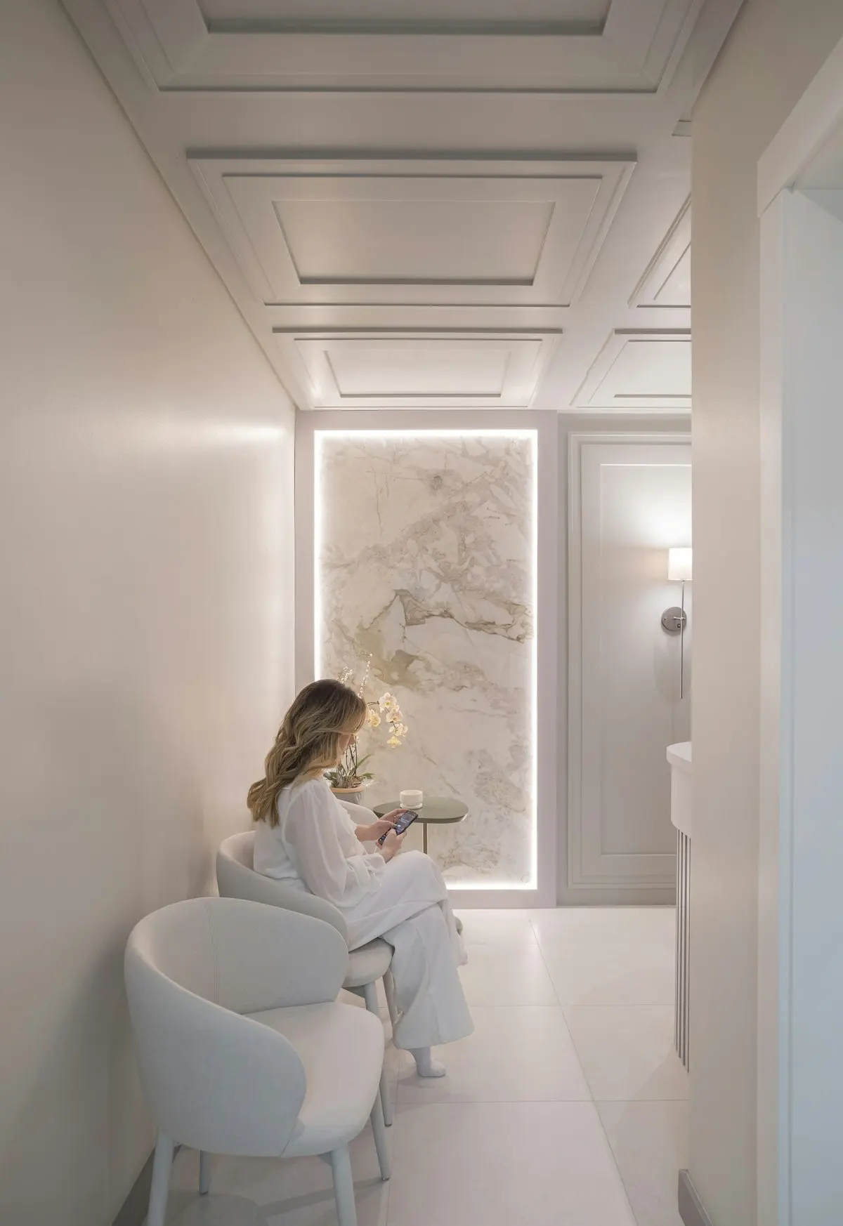 Calm white clinic waiting room with a client reading